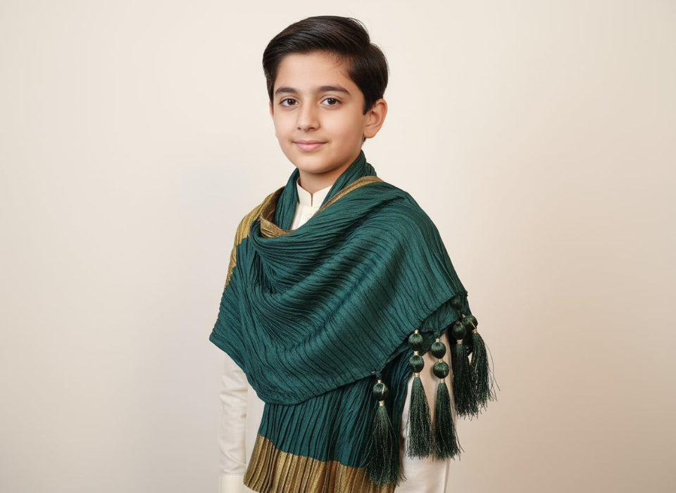 Young boy wearing a green shawl with tassels on a beige background