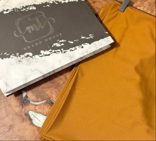 Mustard yellow fabric on a wooden surface with a branded box.