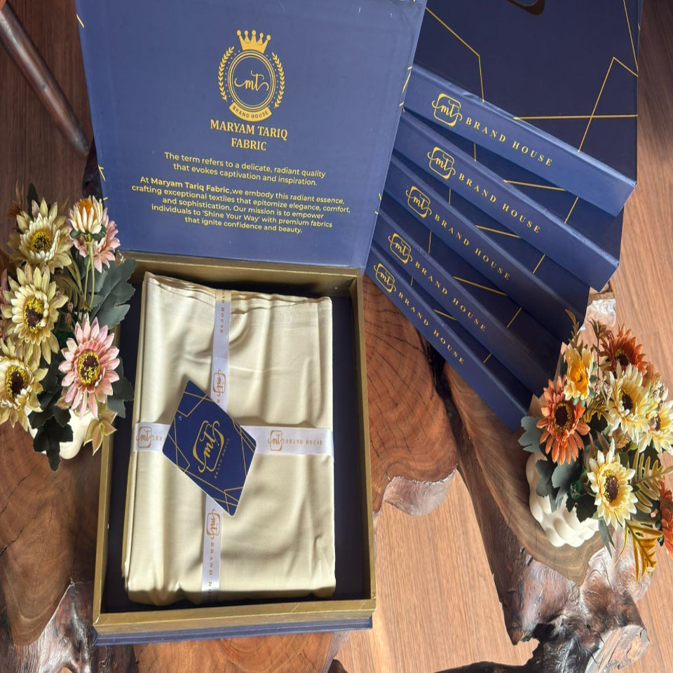 Set of blue books with a gold box containing a white item on a wooden surface with flowers.