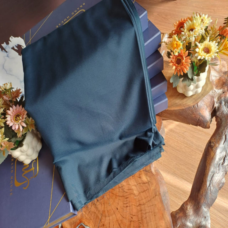 Blue fabric on a wooden table with decorative flowers and a box.