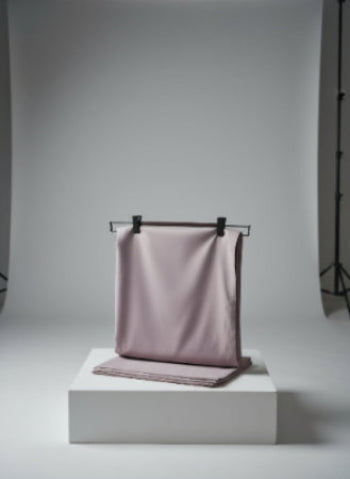 Purple fabric draped over a black rod on a white platform with a gray background