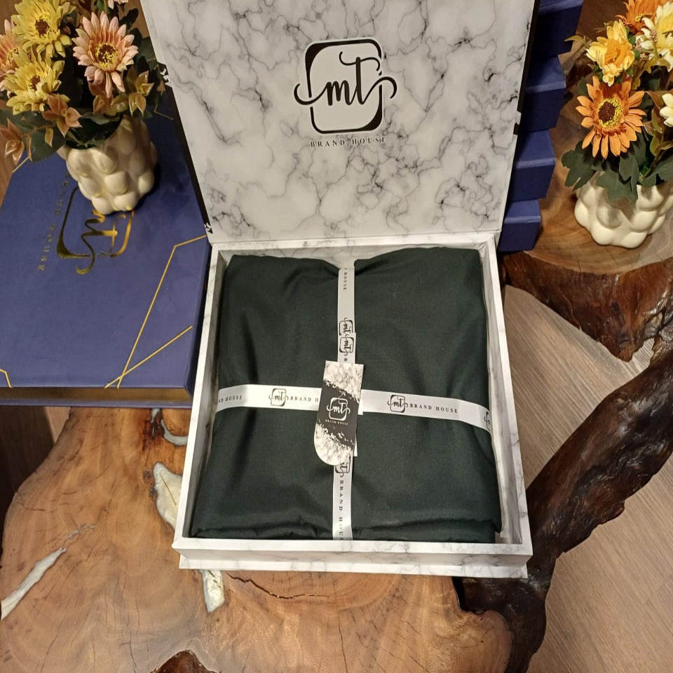 Marble-patterned box with a black garment and measuring tape, surrounded by decorative flowers on a wooden surface.